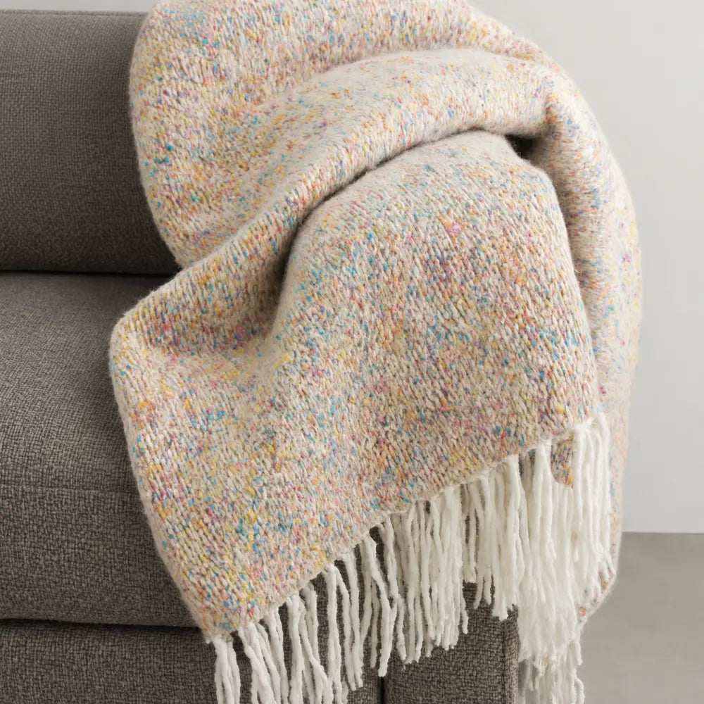 Plaid TWID jacquard multicolore con frange disteso sul divano
